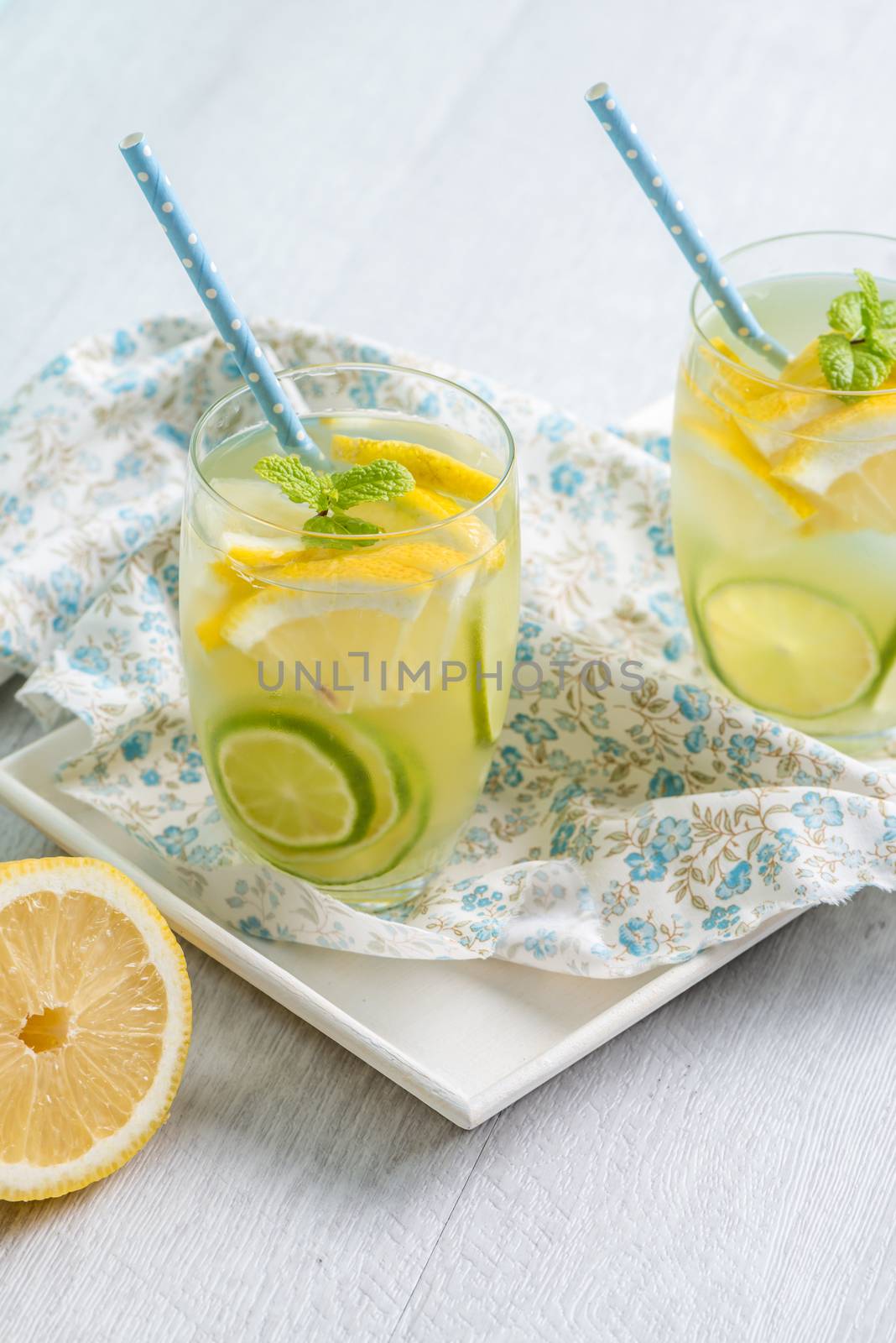 Summer citrus fruits drink on wooden background. Detox citrus infused flavored water. Refreshing summer homemade cocktail with lemon. Fresh lemon and lemonade on wooden background