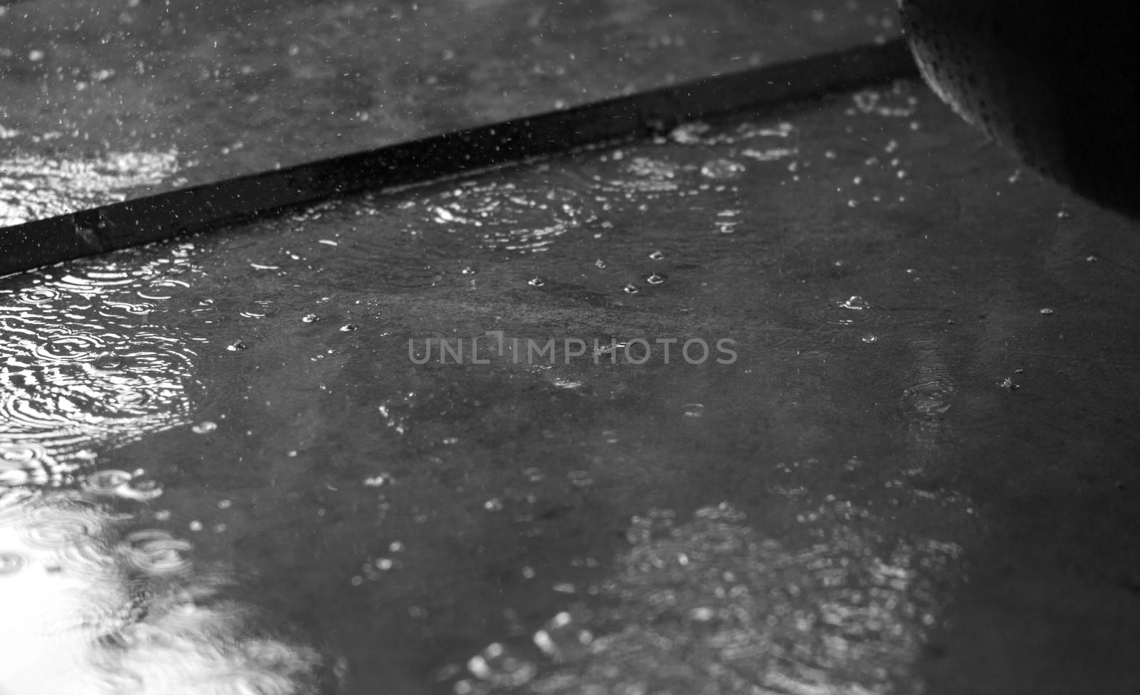 BLACK AND WHITE PHOTO OF RAIN PUDDLES WITH RAINDROPS