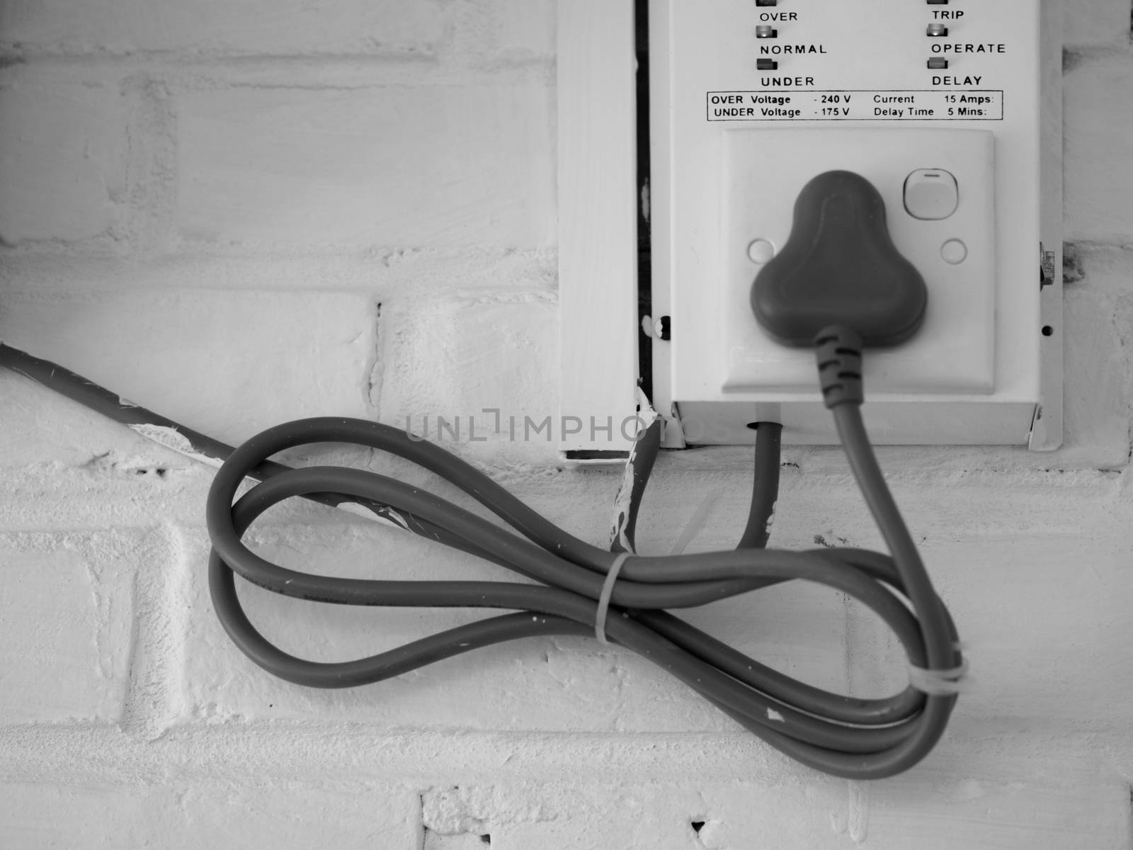 BLACK AND WHITE PHOTO OF ELECTRICAL CABLE ON WHITE BRICK WALL