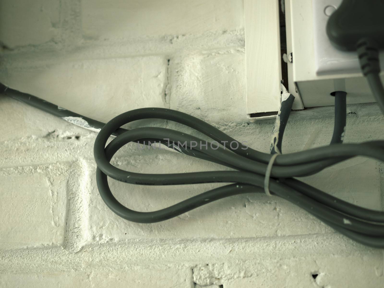 COLOR PHOTO OF ELECTRICAL CABLE ON WHITE BRICK WALL