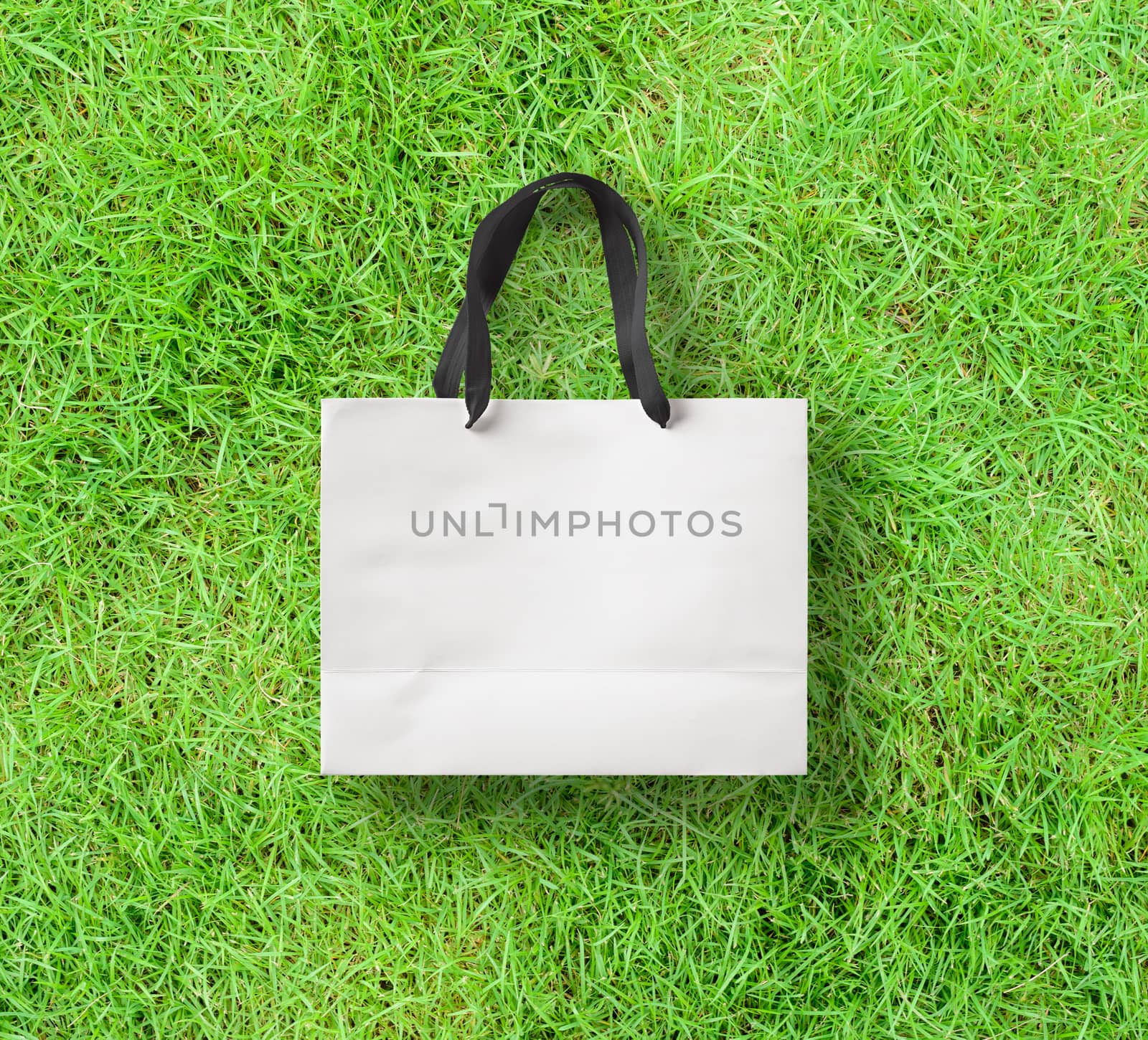 paper bag for shopping on a grass background by boys1983@mail.ru