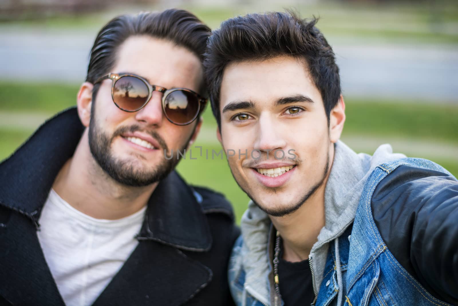 Two young men taking selfie while outdoors, point of view of the camera itself