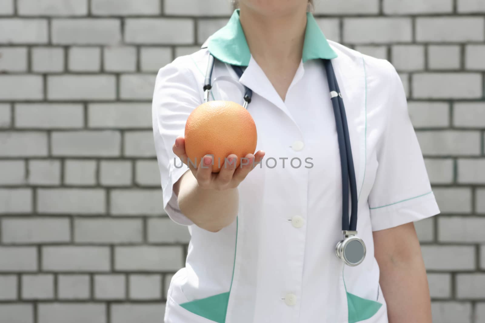 Medicine concept doctor. Diet and proper nutrition. Vitamin orange ripe. On a white brick wall background. Keeps the fruit. Photo for your design