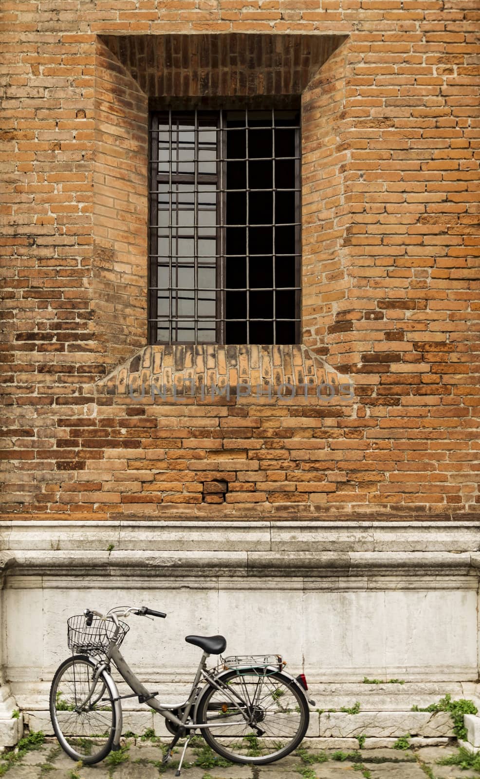 Old bicycle parked on a building wall in Ravenna, Italy