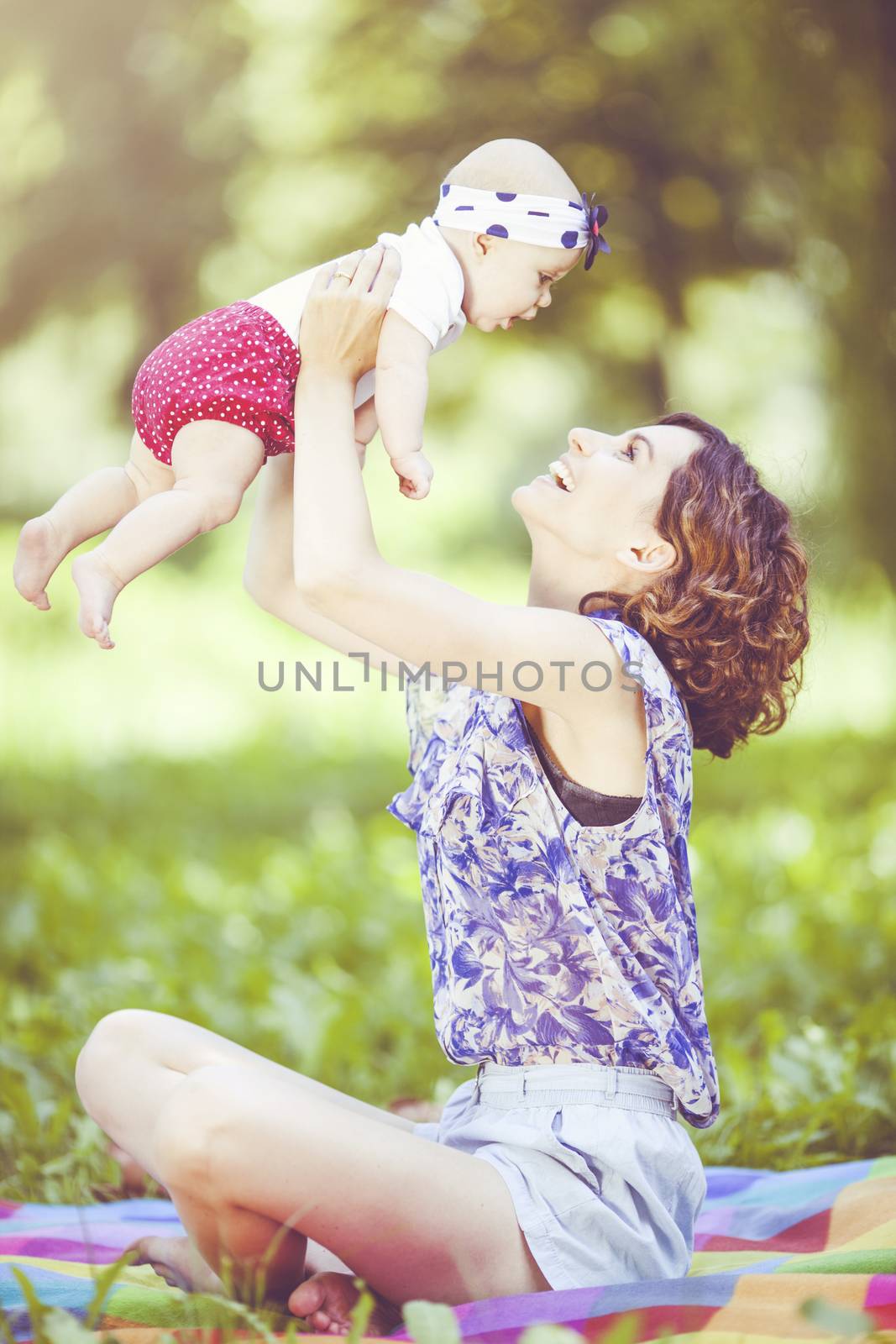 Young beautiful mother sits on blanket with her daughter during a picnic in the park