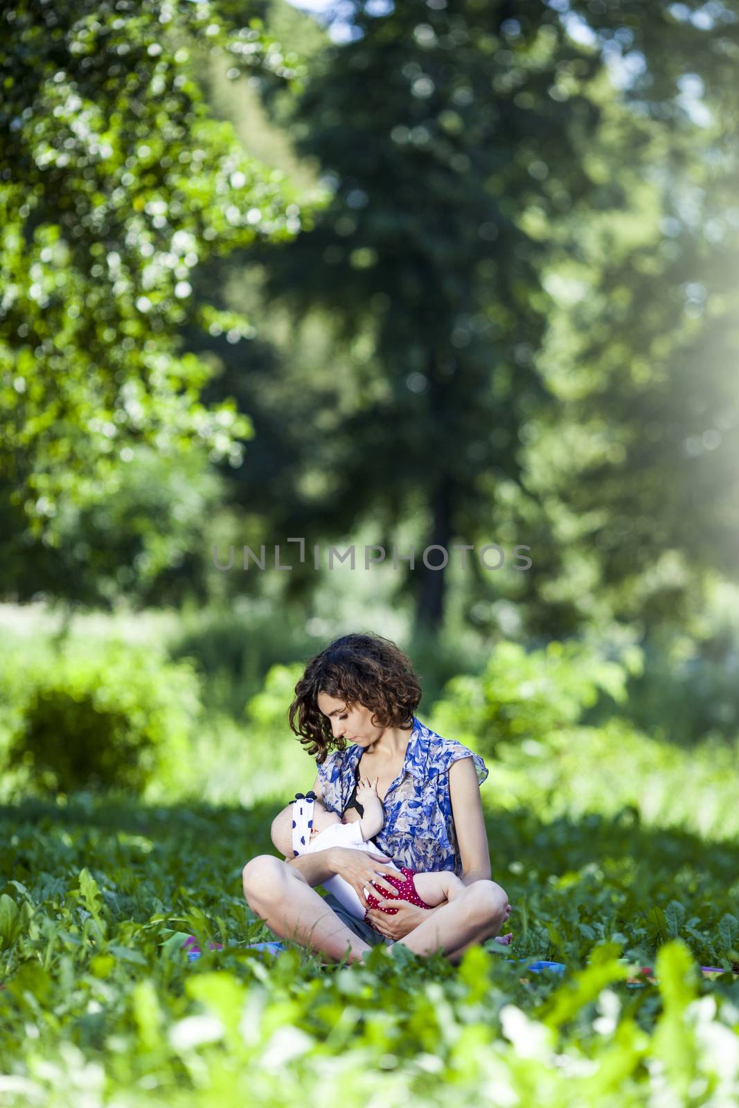 Young beautiful mother sits on blanket with her daughter during a picnic in the park