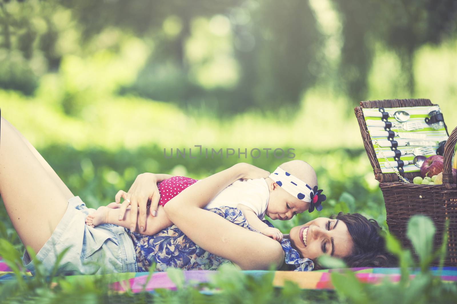 Young beautiful mother sits on blanket with her daughter during a picnic in the park