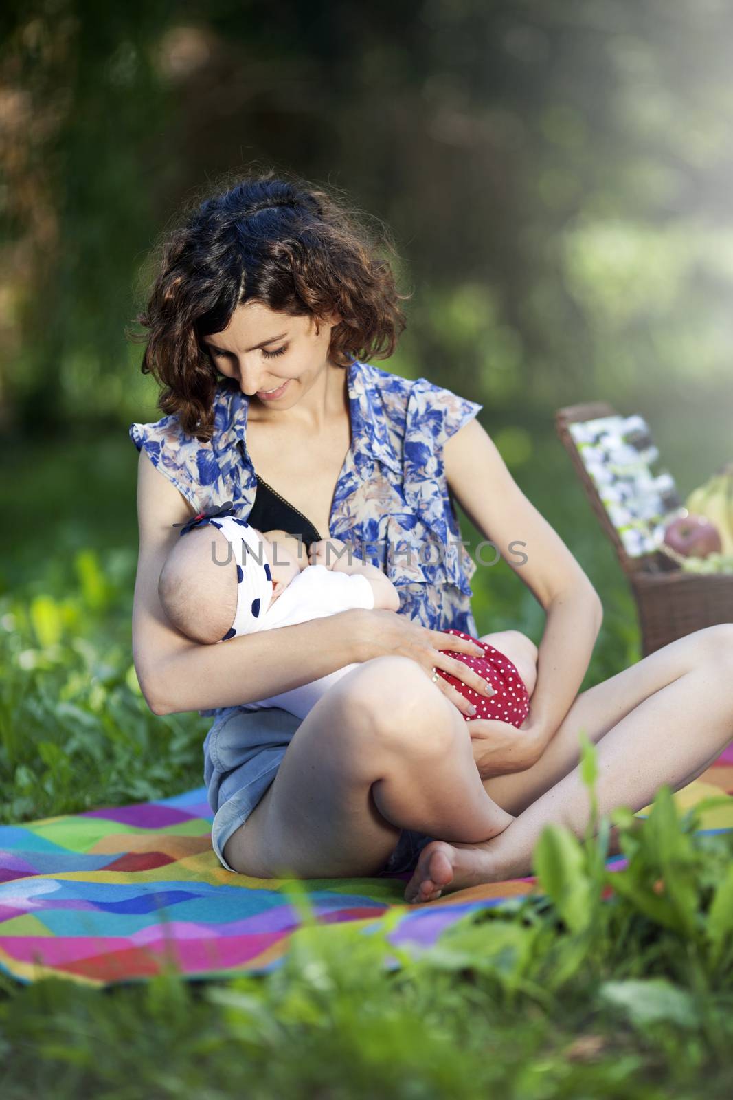 Young beautiful mother sits on blanket with her daughter during a picnic in the park