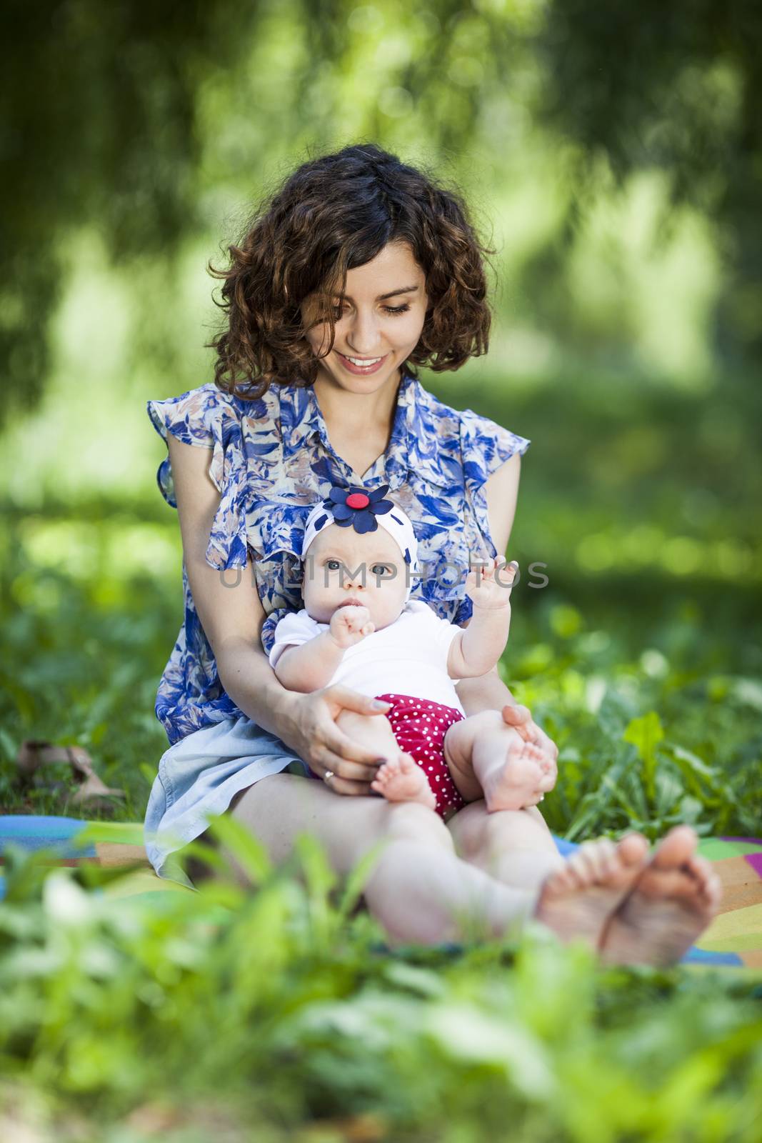 Young beautiful mother sits on blanket with her daughter during a picnic in the park