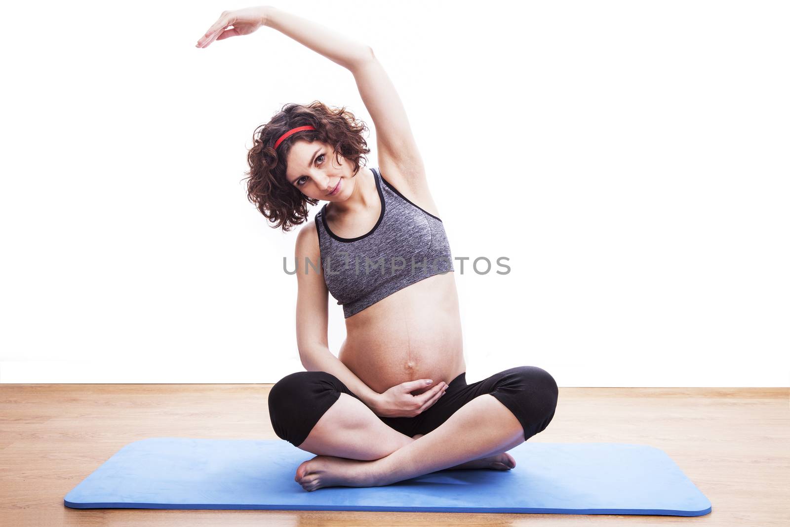 young pregnant woman exercises on the mat. Isolated shot