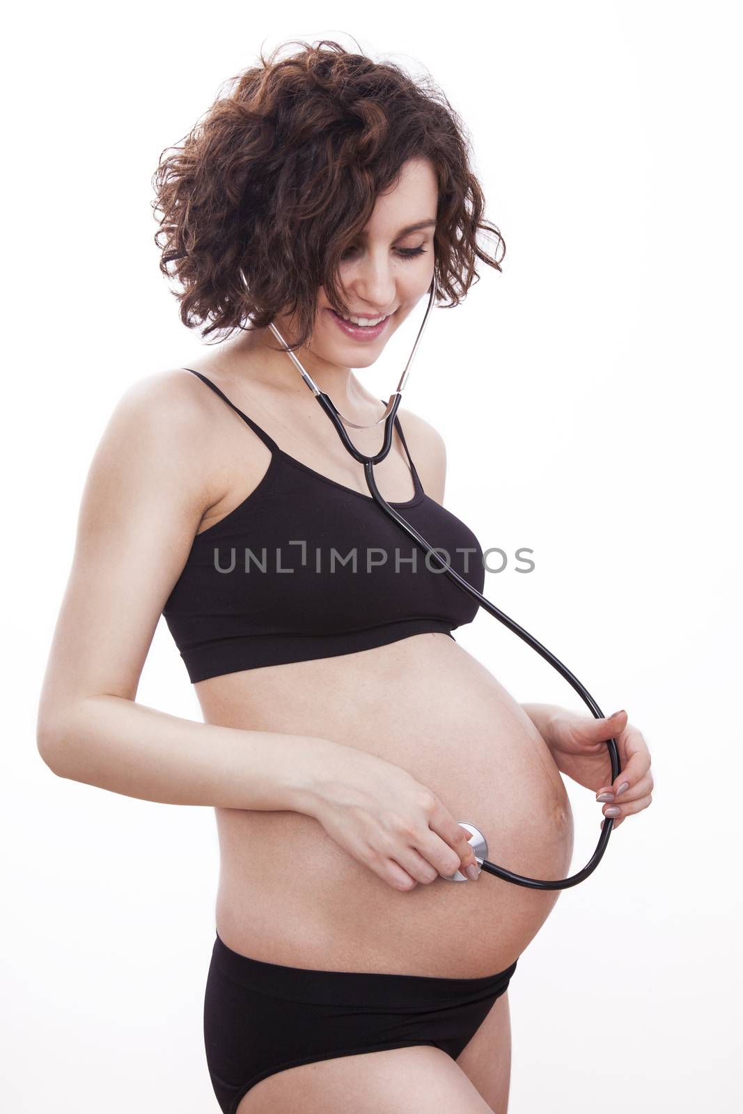 Pregnant woman listens to her child through a stethoscope.