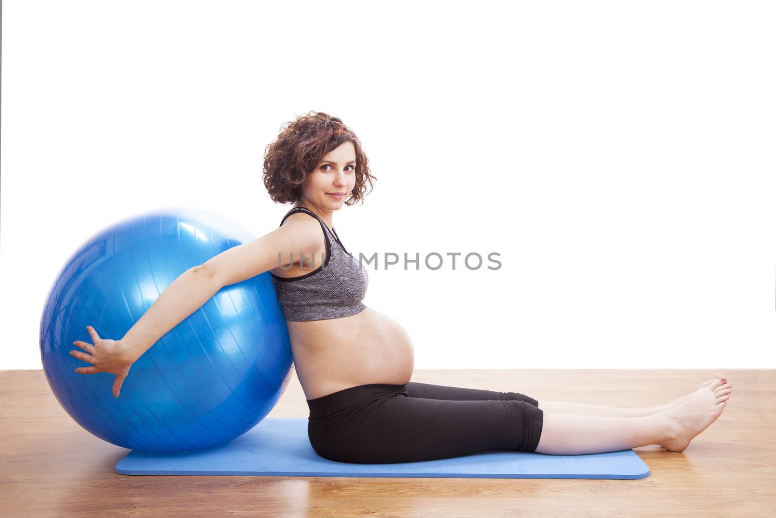 Young pregnant woman exercises with the ball.