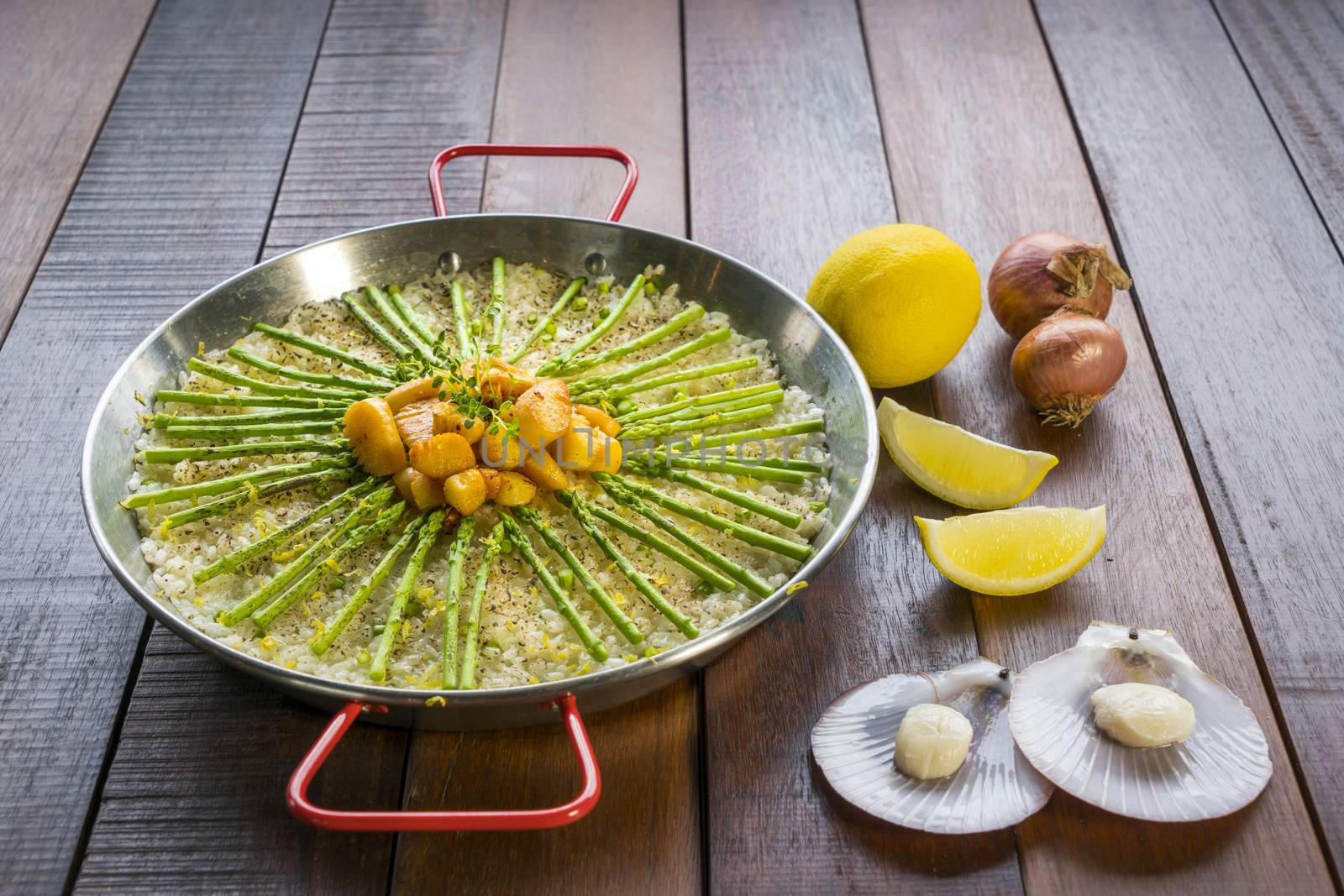 Paella with scollops and asparagus in traditional pan.