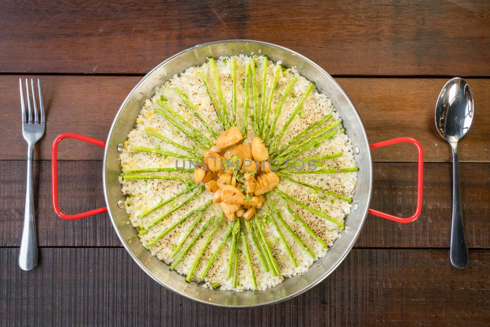Paella with scollops and asparagus in traditional pan.