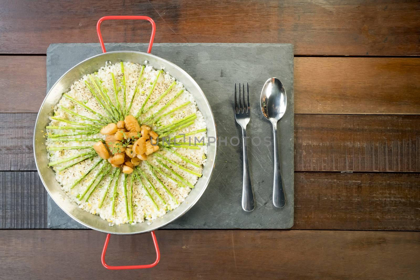 Paella with scollops and asparagus in traditional pan.