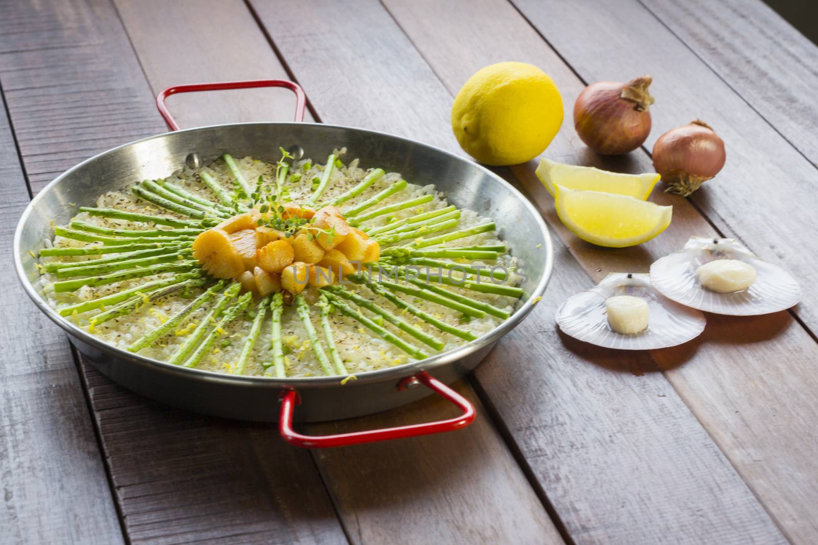 Paella with scollops and asparagus in traditional pan.