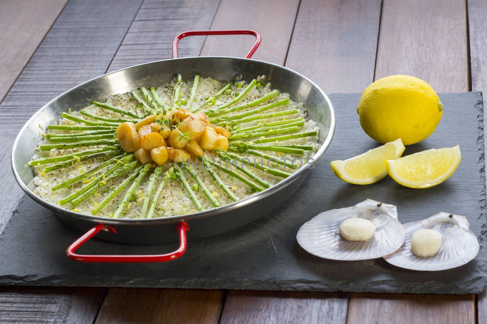 Paella with scollops and asparagus in traditional pan.