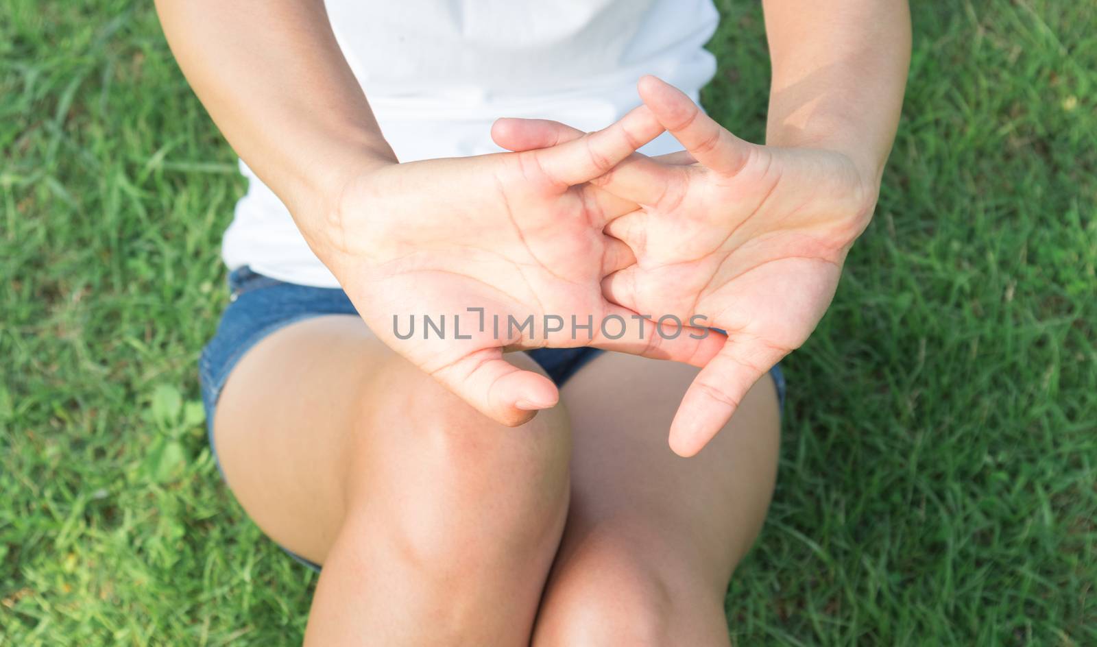 Closeup woman stretching exercises finger in the park with sun light, selective focus