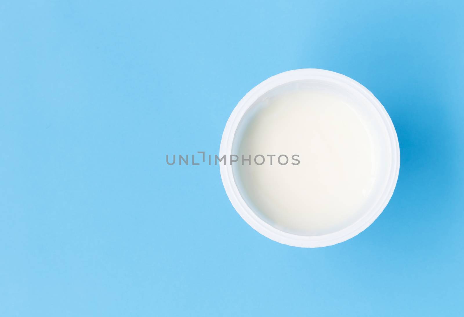 Closeup top view greek yogurt in white cup with blue background