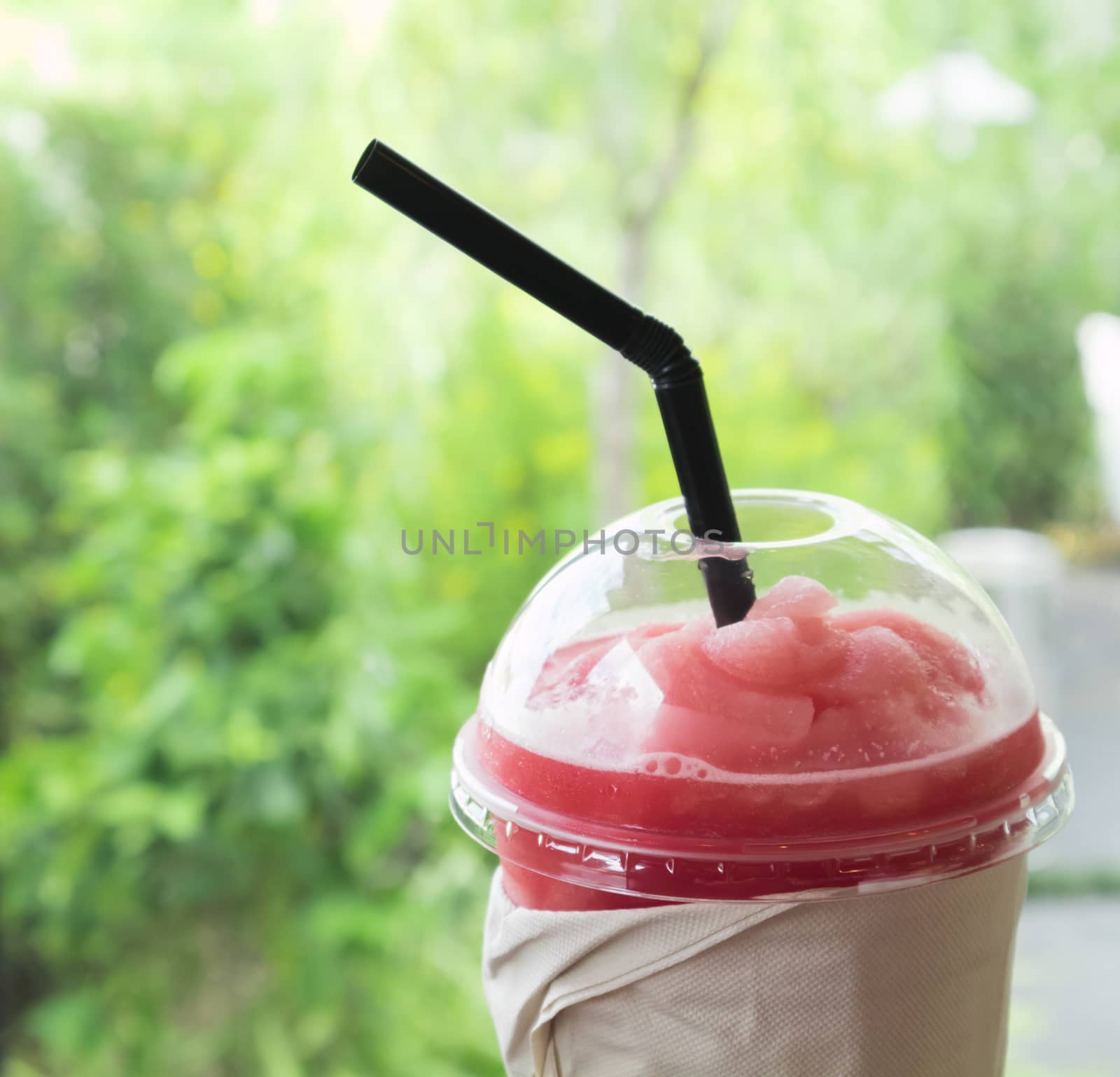 Closeup of watermelon smoothie in plastic glass on table, selective focus