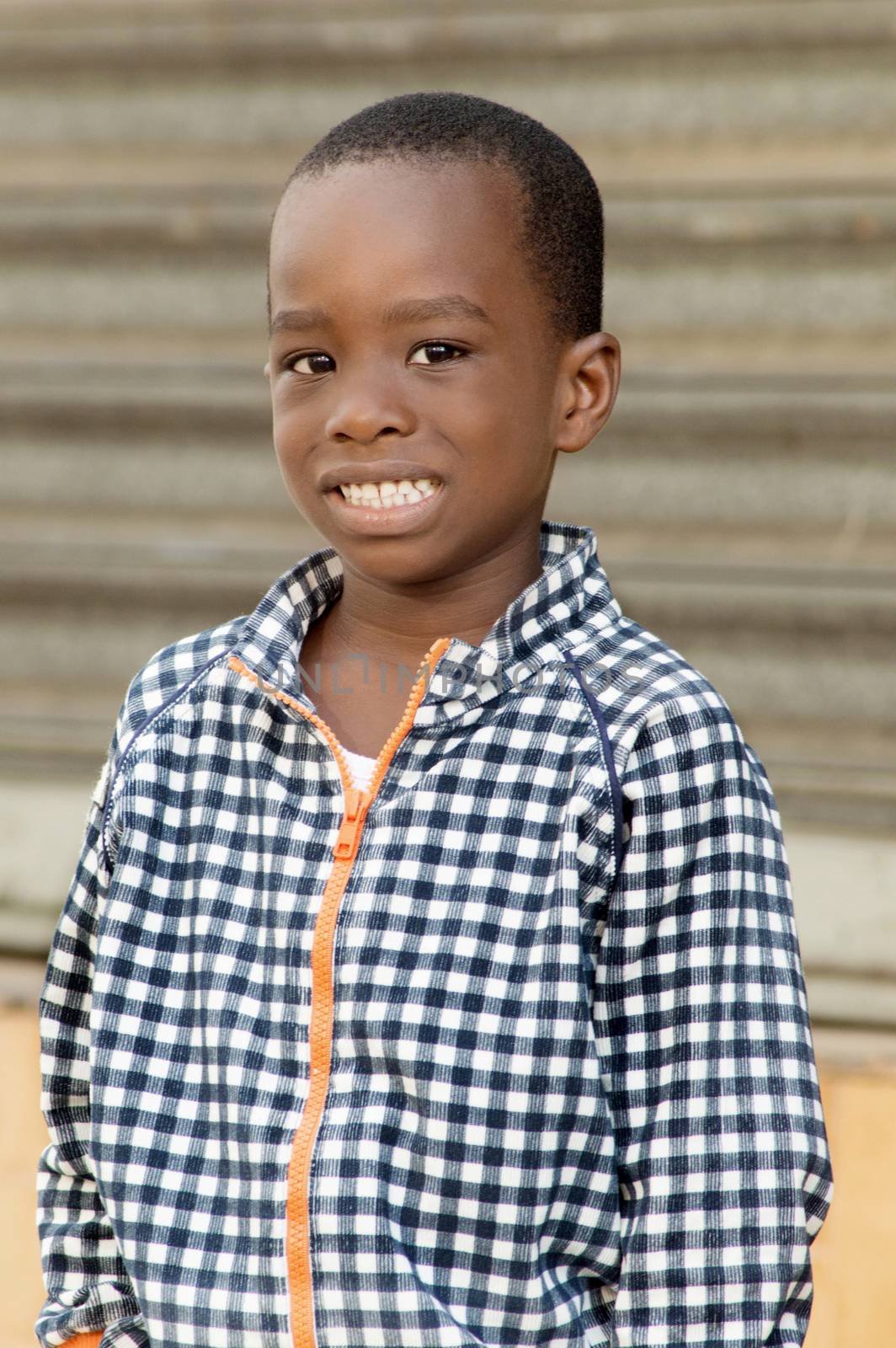 child standing near a gate, waiting for his mother.