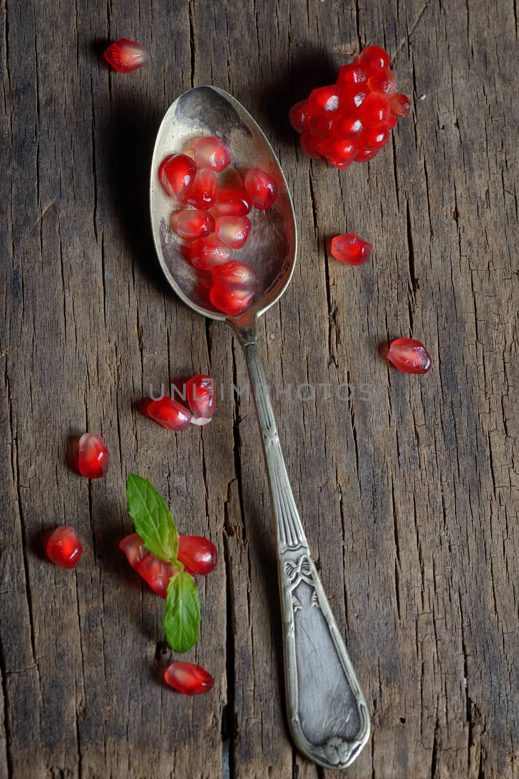 Ripe pomegranate and spoon on wooden table