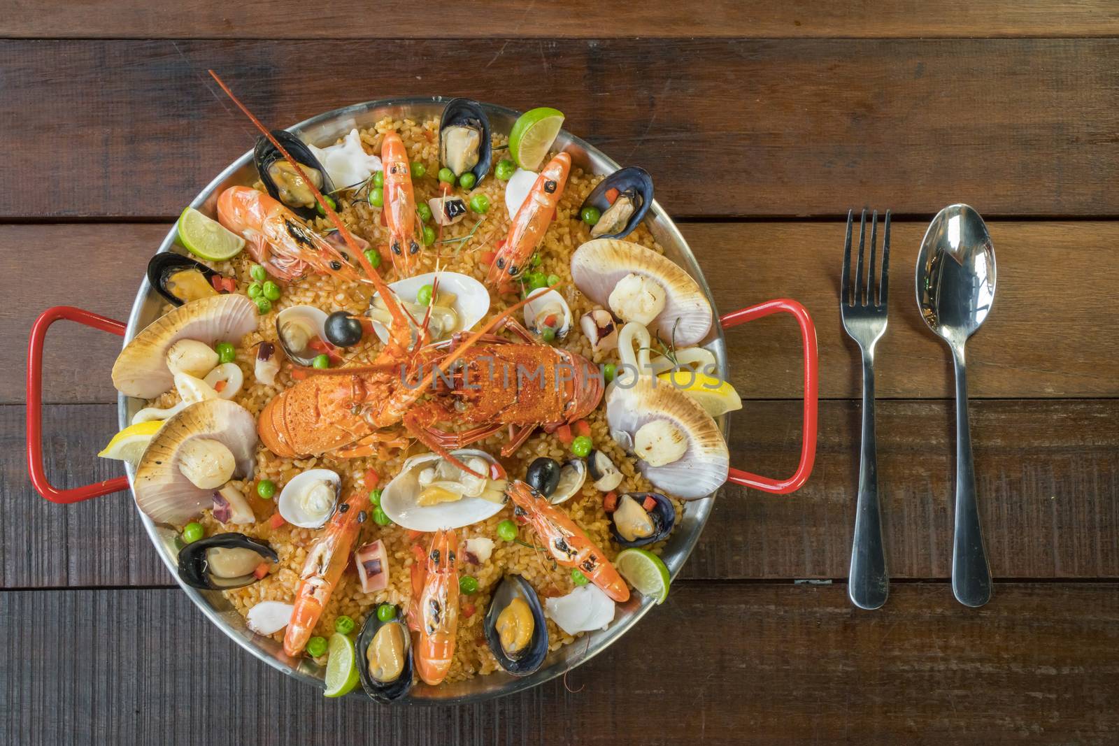 Gourmet seafood Valencia paella with fresh langoustine, clams, mussels and squid on savory saffron rice with prawn, scollops, mussels and lime slices, close up view