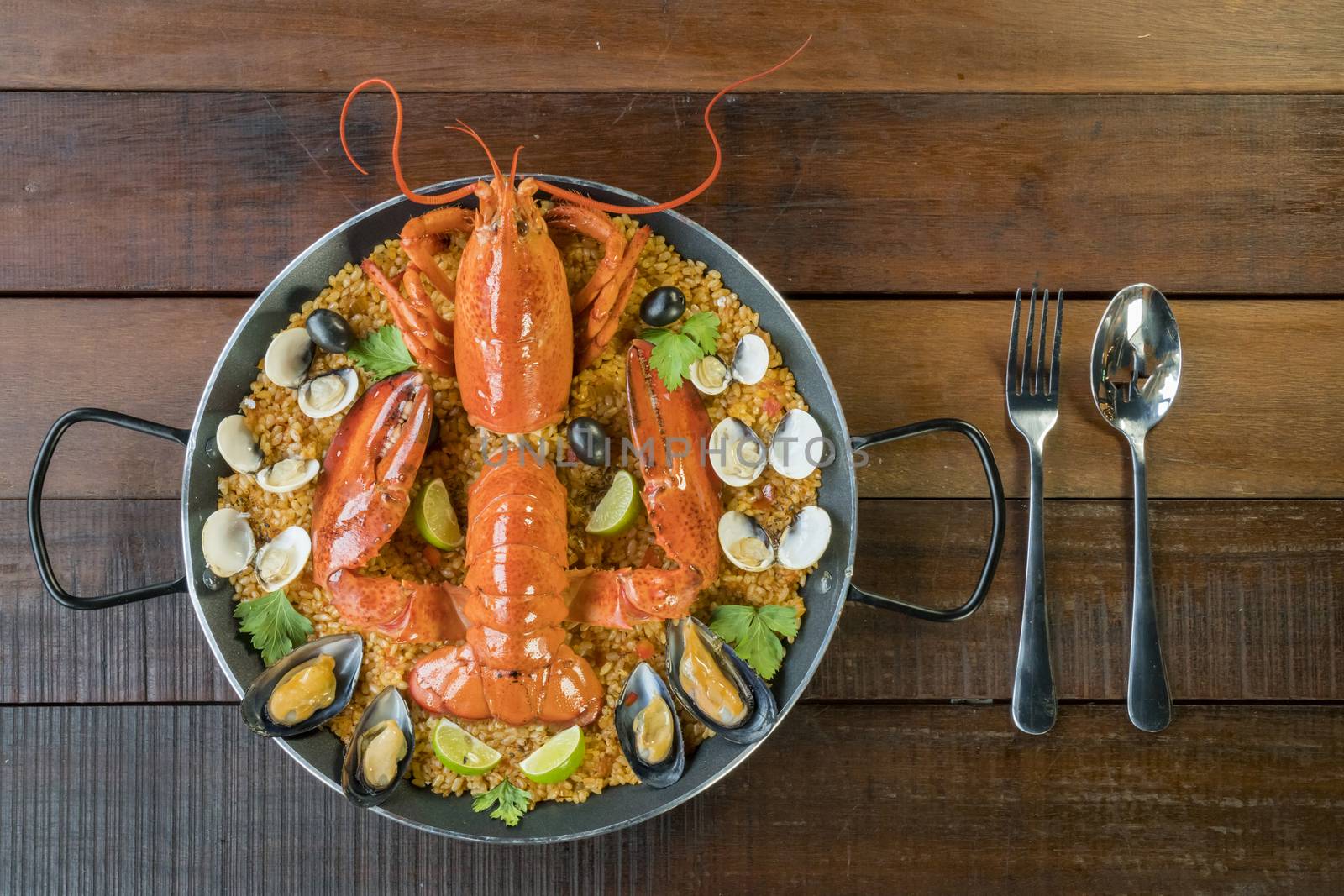 Gourmet seafood Valencia paella with fresh langoustine, clams, mussels and squid on savory saffron rice with peas and lemon slices, above view