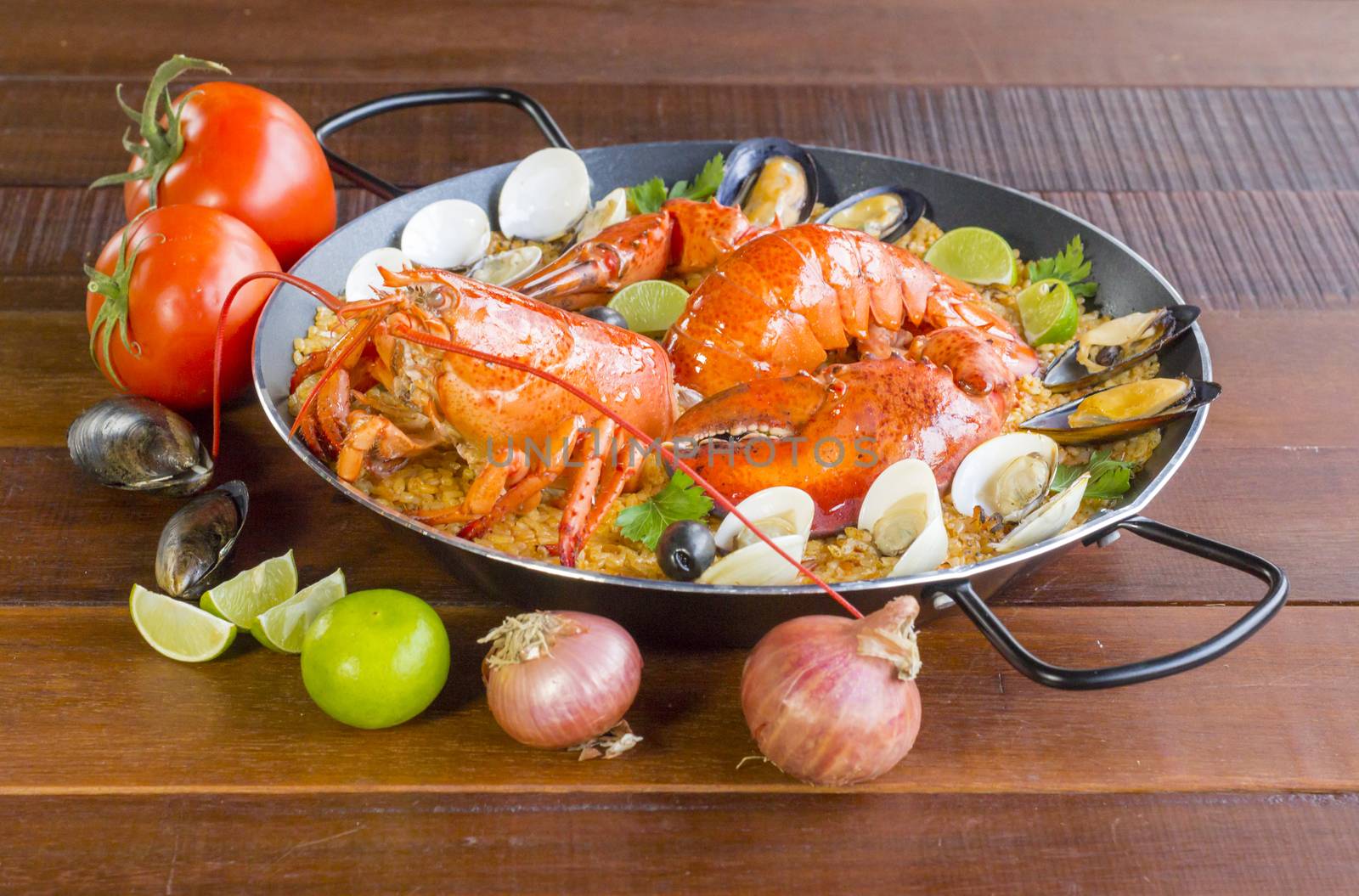 Gourmet seafood Valencia paella with fresh langoustine, clams, mussels and squid on savory saffron rice with peas and lemon slices, close up view