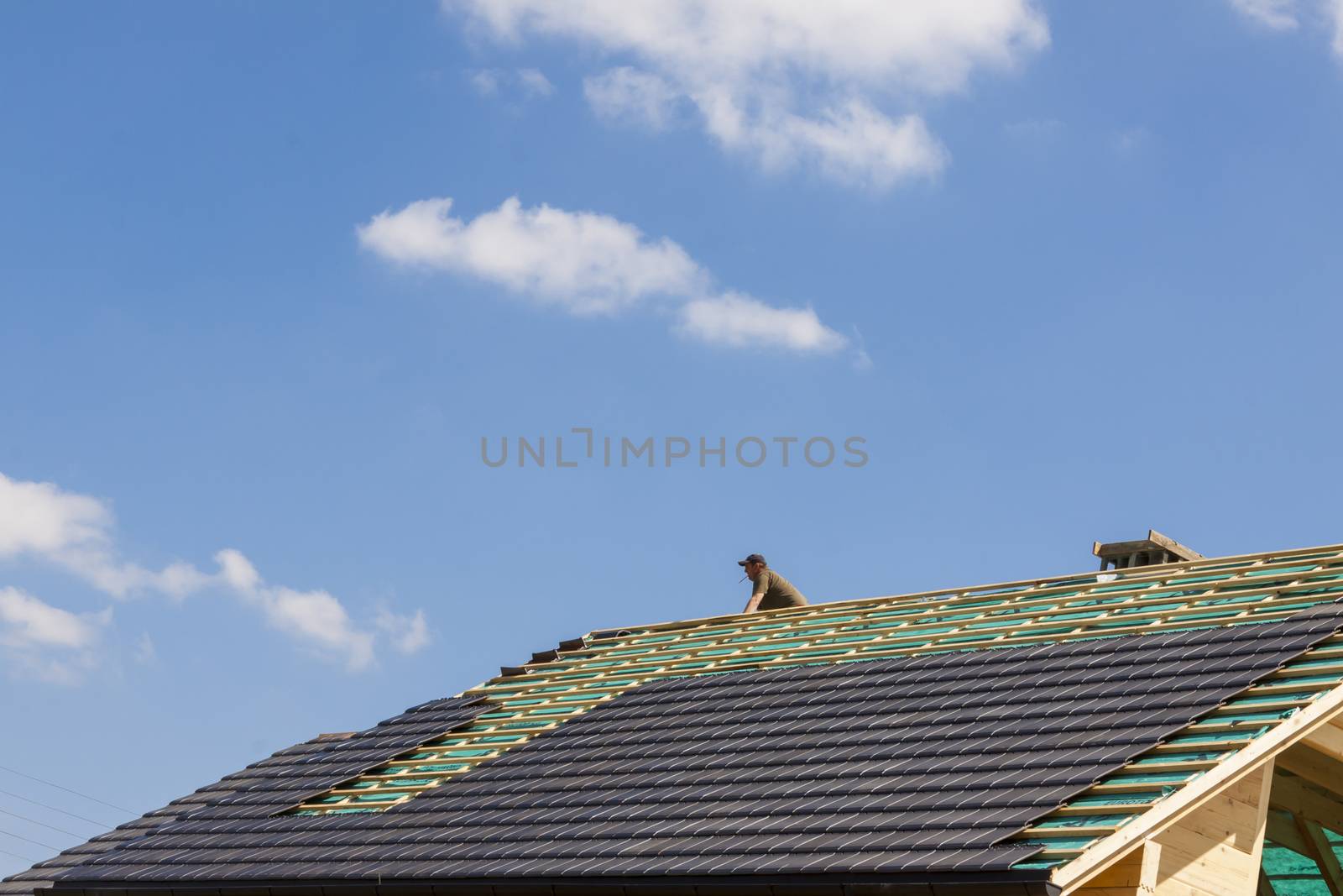 Roofer working on the top of the unfinished roof