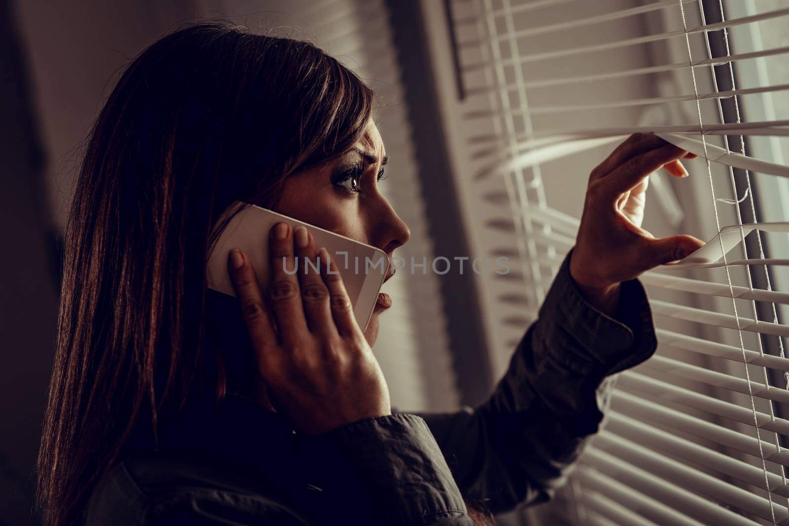 Young abused woman scared looking through the window seeking safety.