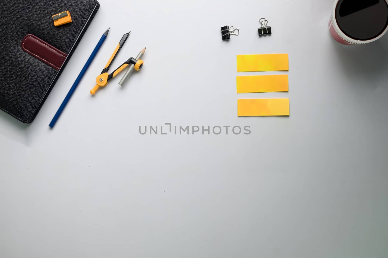 Top view of copy space of white working table work space with notebook, cup,note paper,pencil,clip,calculator and other supplies.