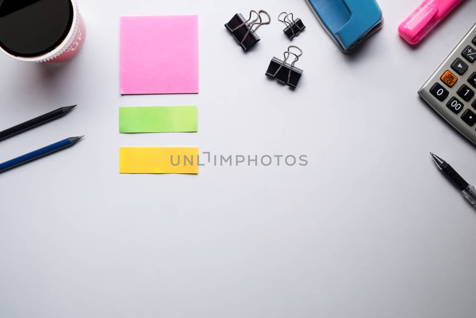 Top view of copy space of white working table work space with notebook, cup,note paper,pencil,clip,calculator and other supplies.
