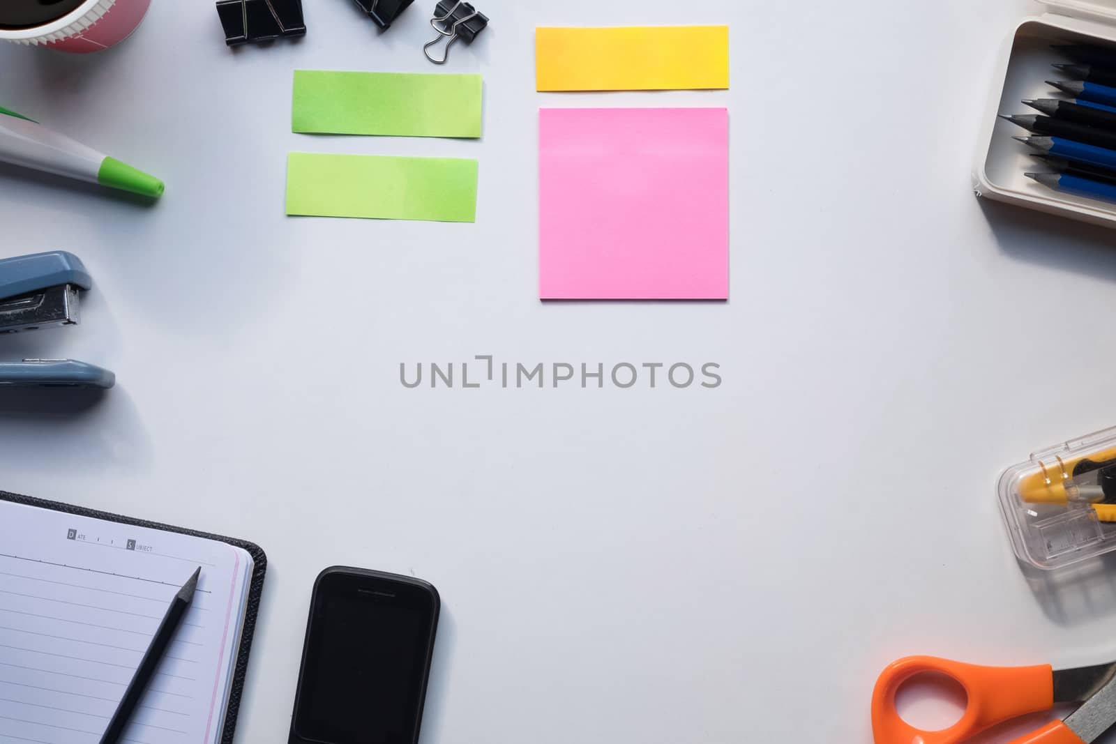 Top view of copy space of white working table work space with notebook, cup,note paper,pencil,clip,calculator and other supplies.