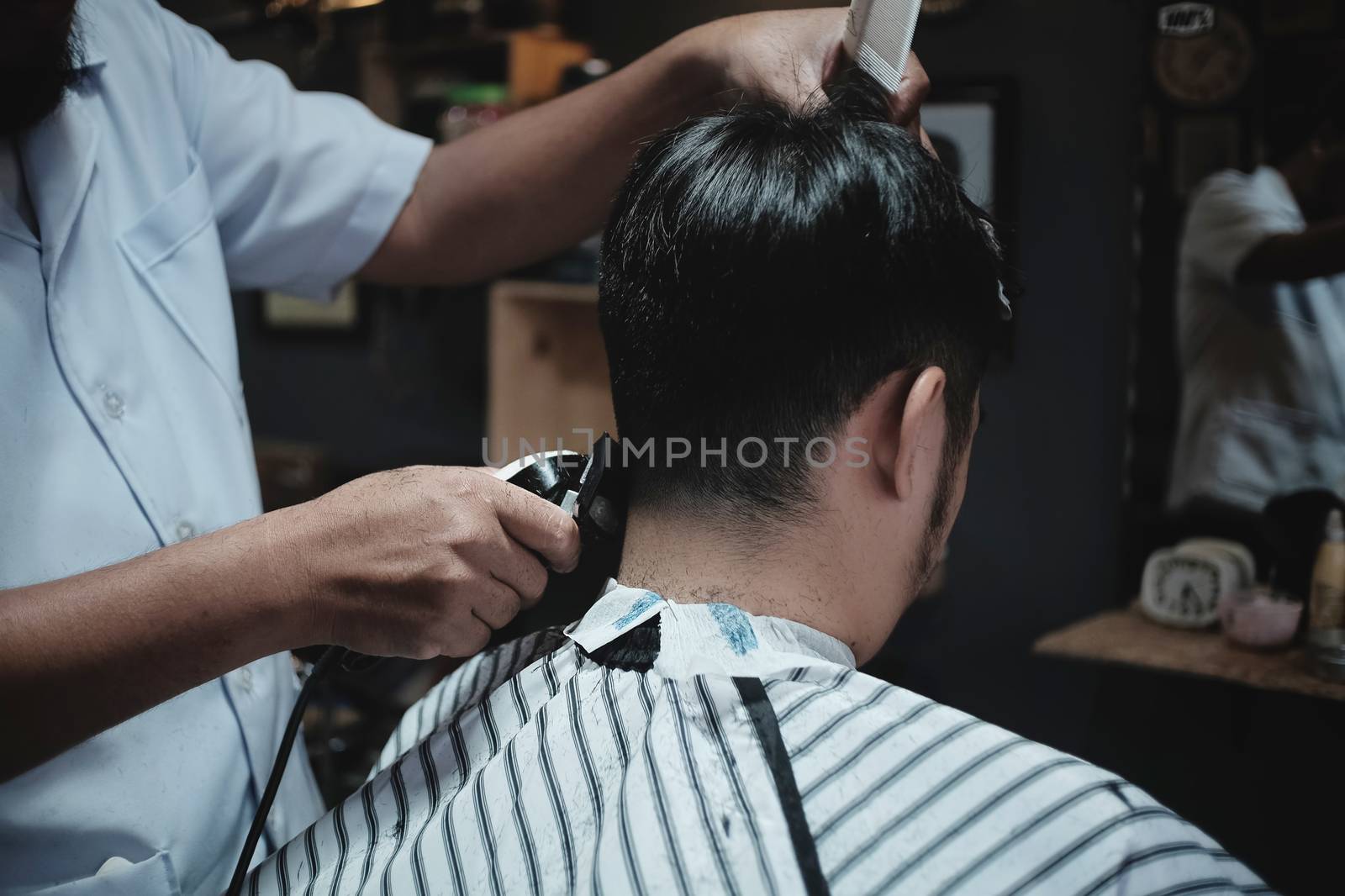 Hairdresser makes hairstyle a man with vintage tone.