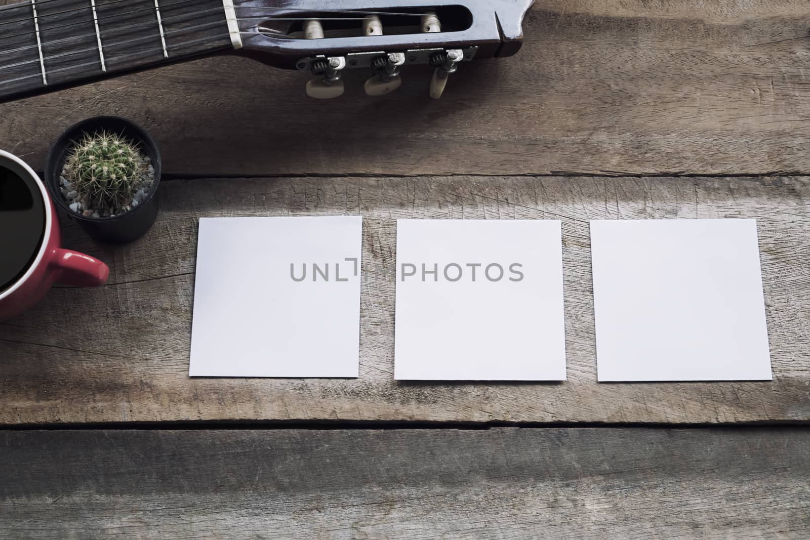 Empty three paper on wood desk and guitar,cup of coffee with copy space.
