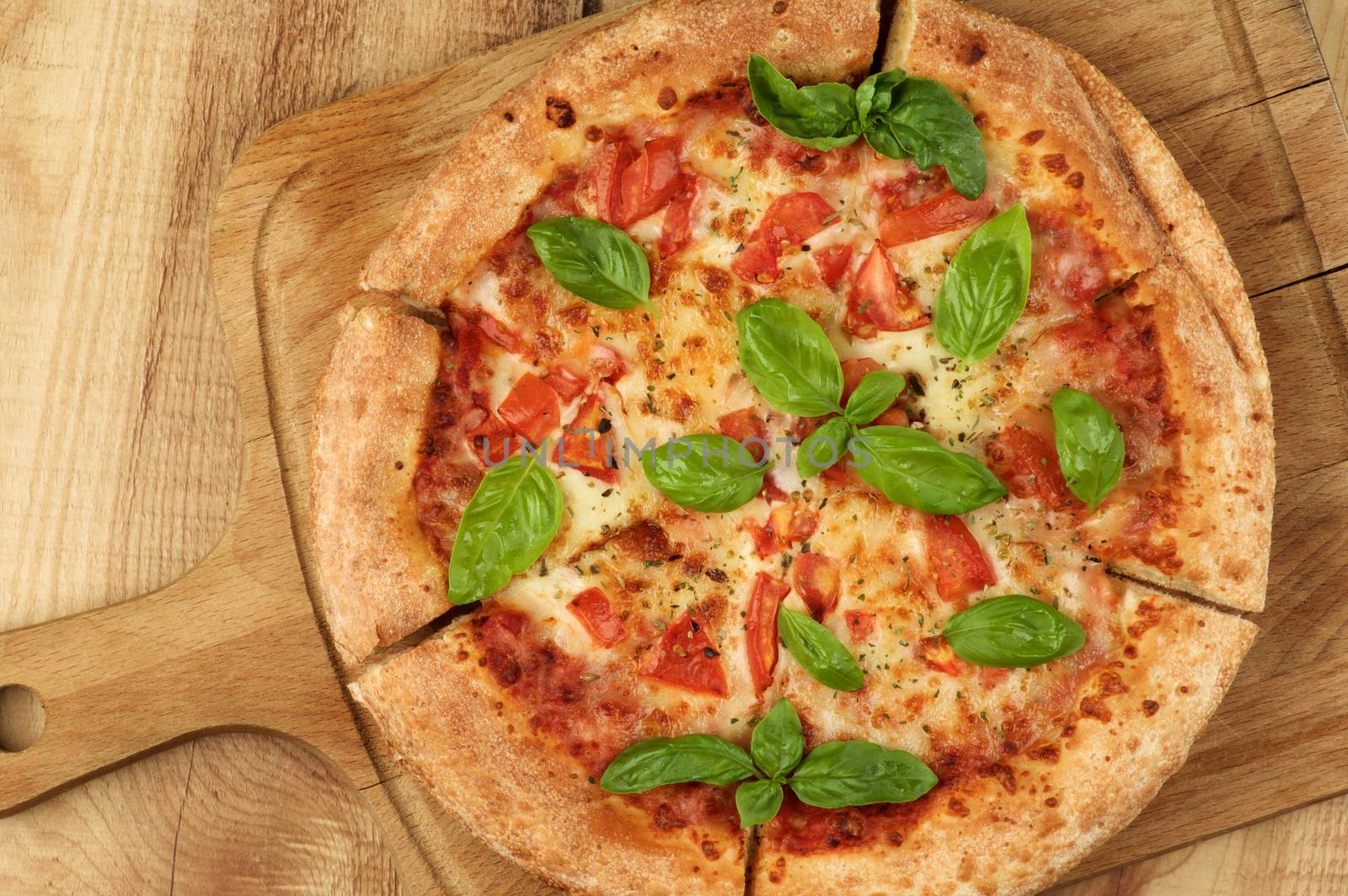 Freshly Baked Margarita Pizza with Tomatoes, Cheese and Basil Leafs on Cutting Board closeup on Wooden background