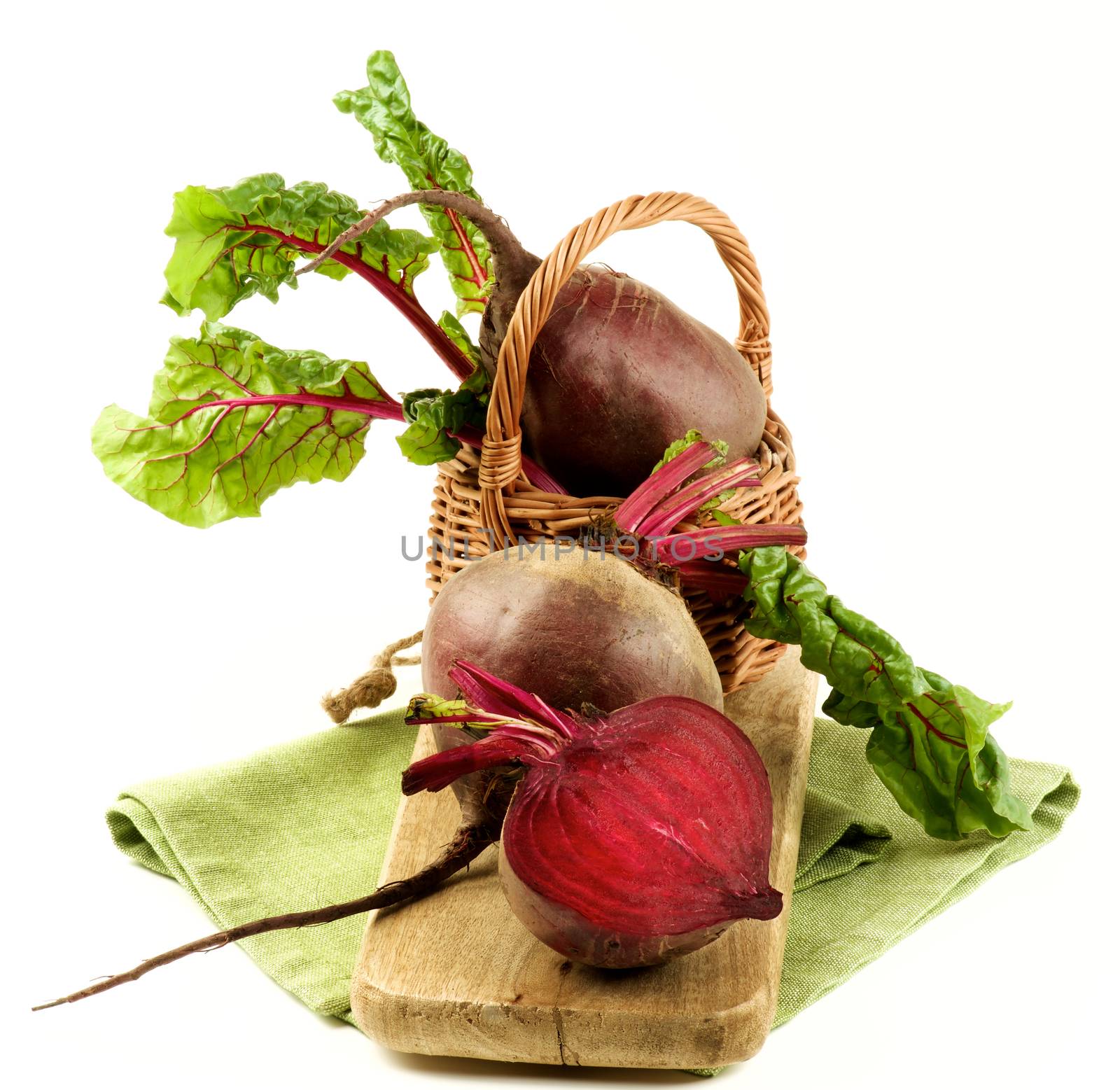 Fresh Raw Organic Beet Roots with Green Beet Tops Full Body and Half in Wicker Basket on Wooden Board and Napkin isolated on White background