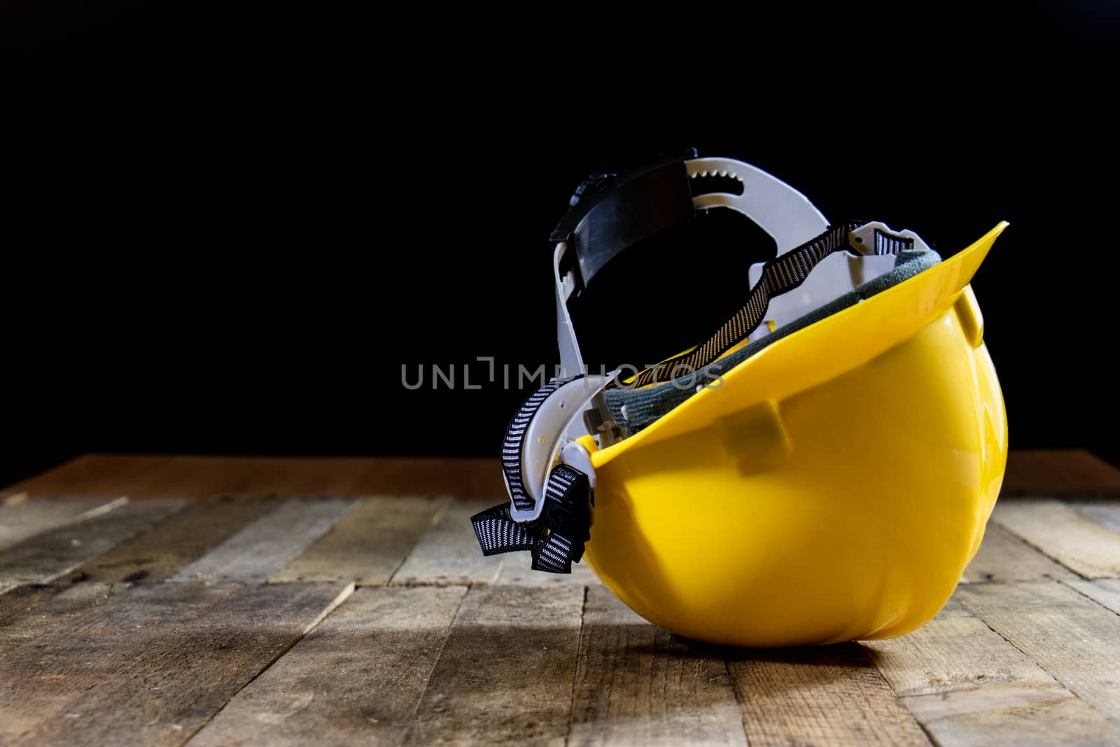 Yellow helmet on an old wooden table. Workshop in the workshop. Wooden table, black background.