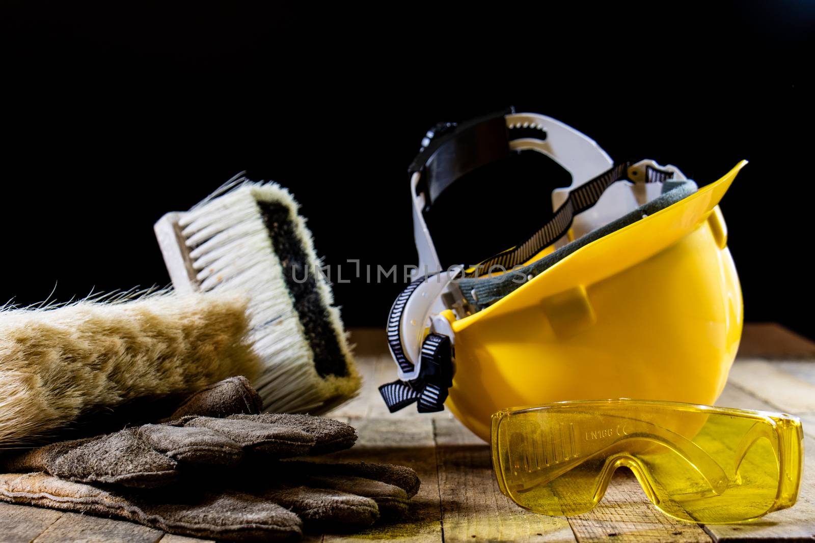 Yellow helmet and carpenter tools. Carpenter and old wooden table. Black background