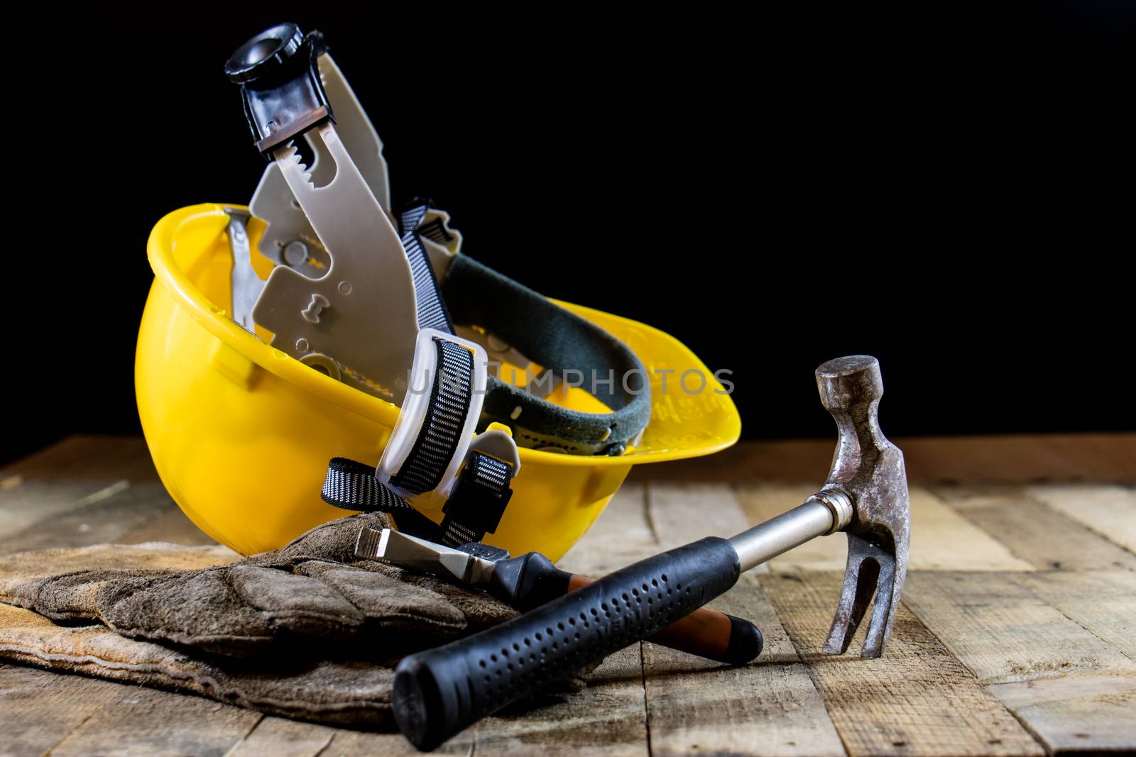 Yellow helmet and carpenter tools. Carpenter and old wooden table. Black background