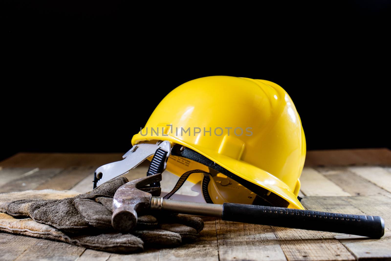 Yellow helmet and carpenter tools. Carpenter and old wooden table. Black background