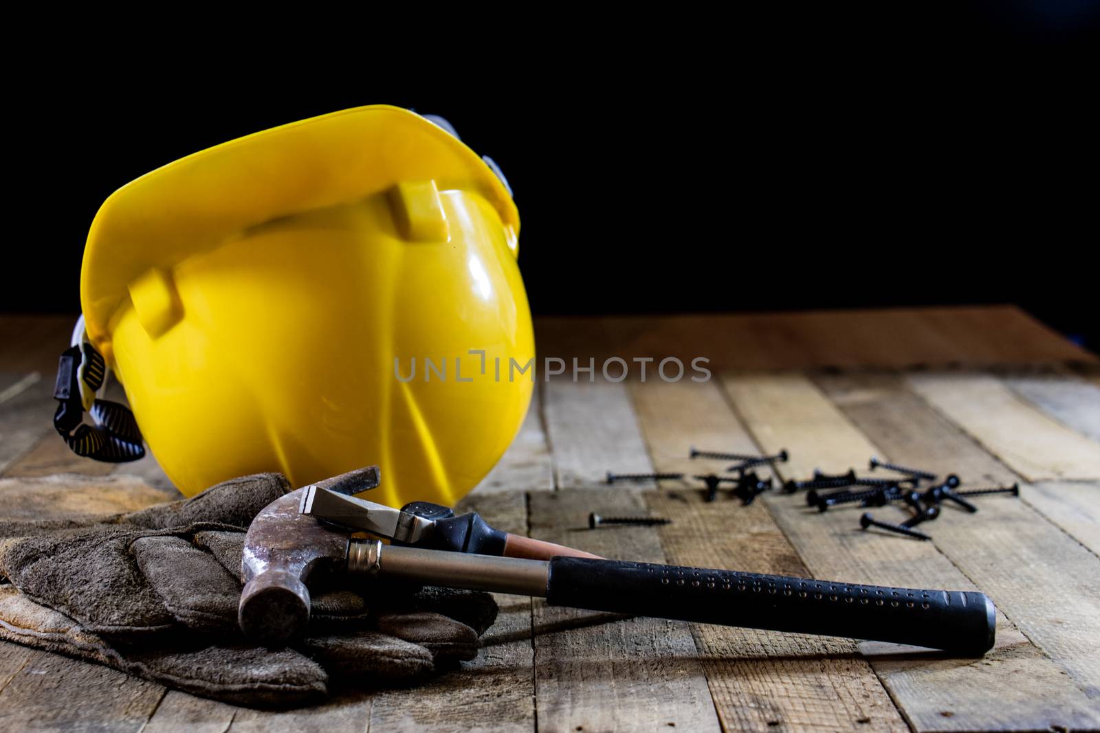 Yellow helmet and carpenter tools. Carpenter and old wooden table. Black background