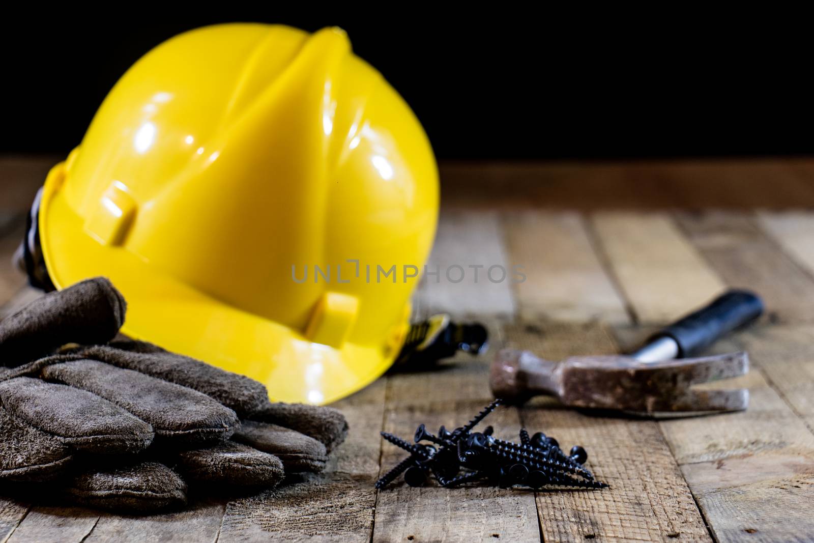 Yellow helmet and carpenter tools. Carpenter and old wooden table. Black background