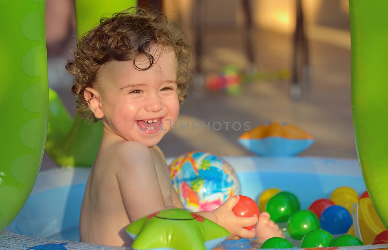 Laughing little girl swimming in the small pool 