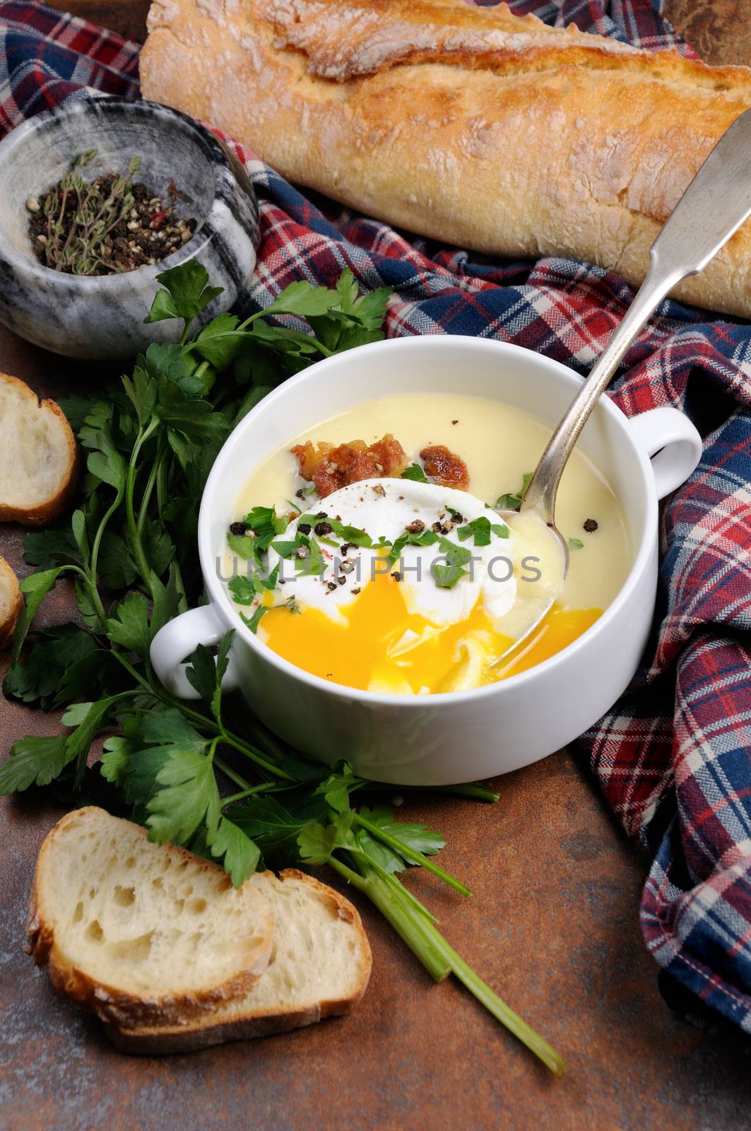 Garlic potato cream soup with bacon and poached eggs, herbs, spices