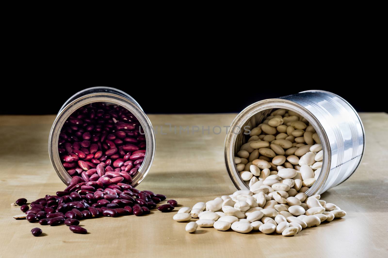 Delicious beans in a metal jar on a wooden kitchen table. Black background.