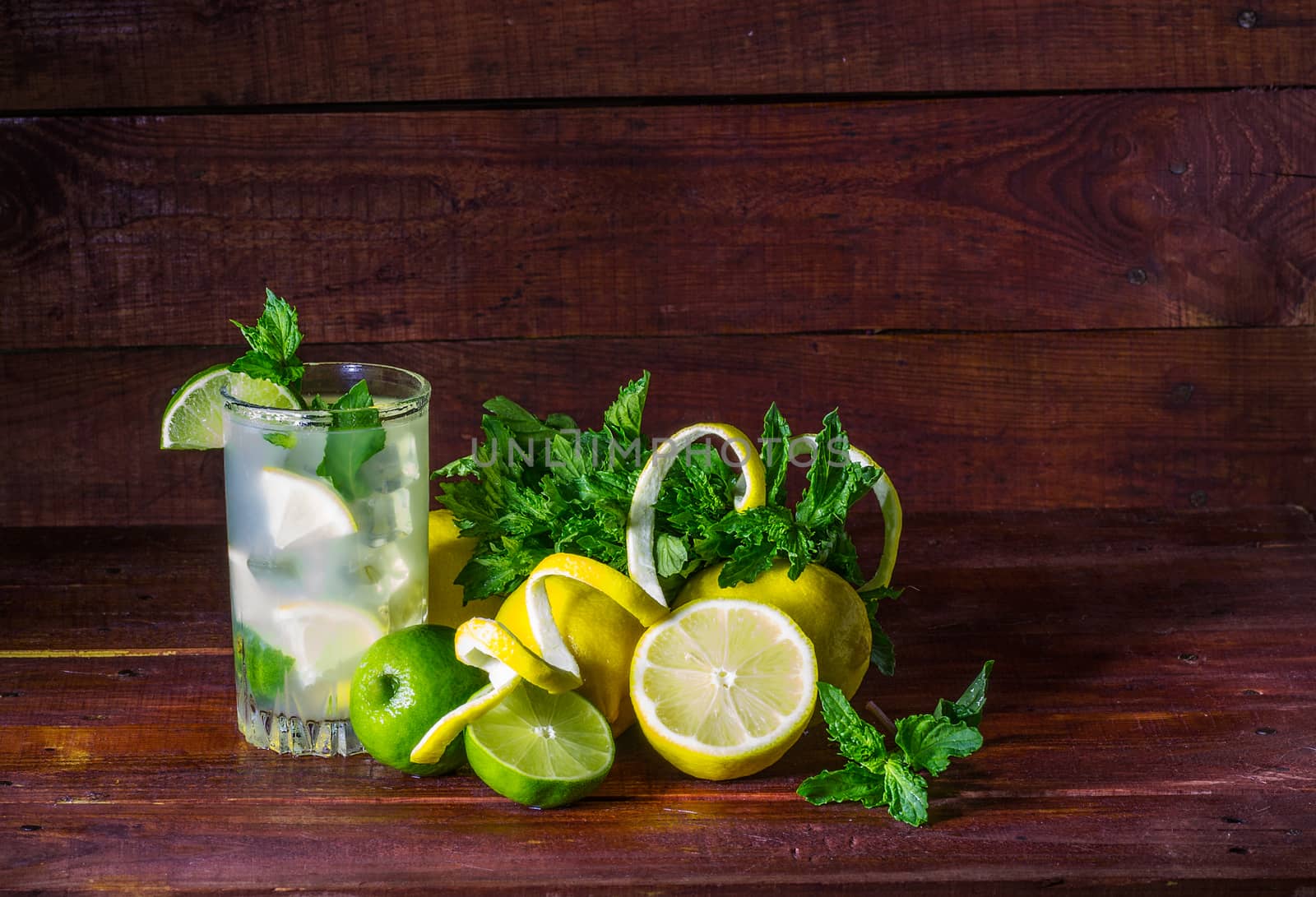 A glass of lemonade with lemon slices, lime, mint and ice