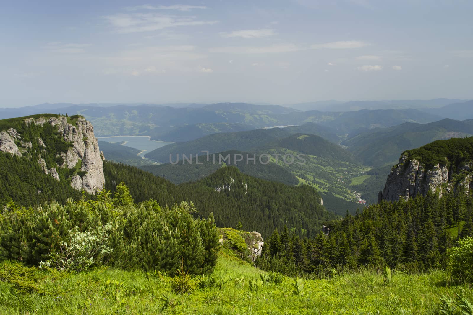 Summer landscape from the top of mountains, green pasture and forest in valley.