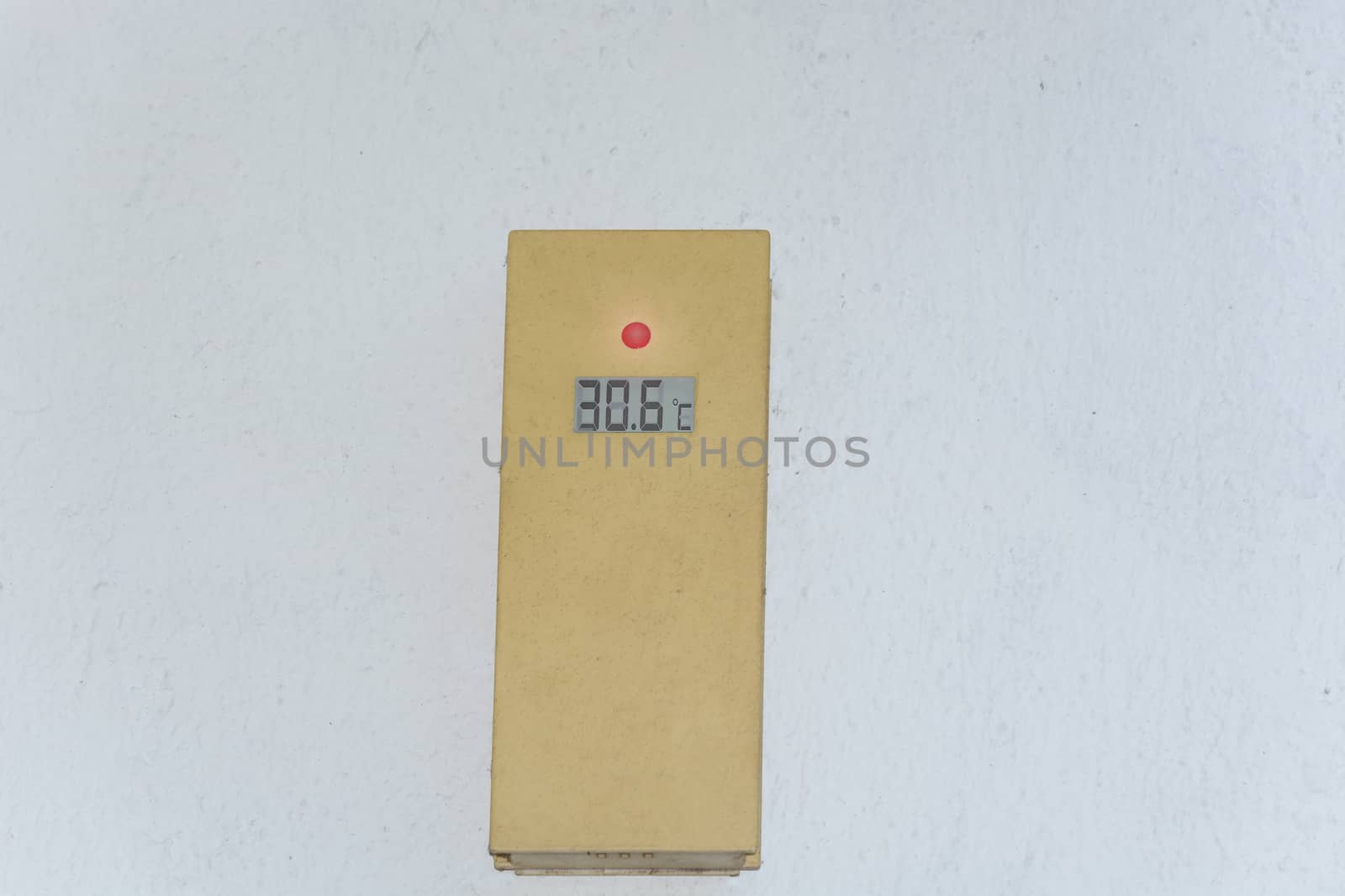 Thermometer on a white exterior wall shows 30 degrees. Concept hot summer day.